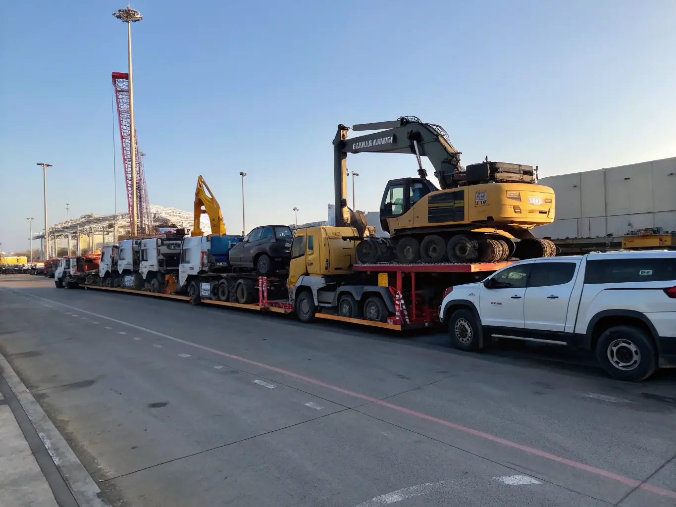 A diverse range of vehicles, including luxury cars, commercial trucks, and specialized equipment, are shown being securely loaded onto a transport carrier, illustrating the variety of vehicles Nothimporta handles.